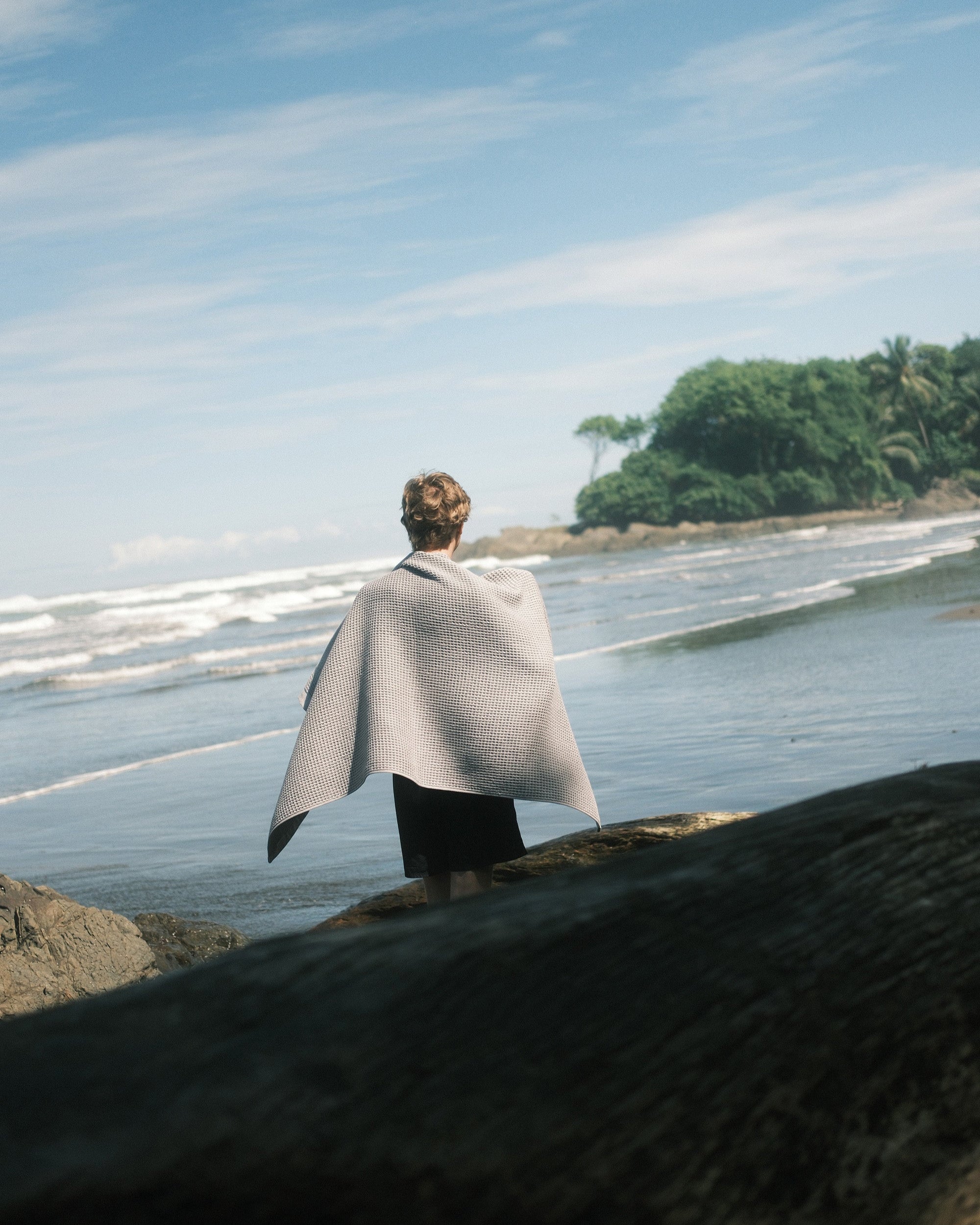 Person drying with a Nossara Imabari Waffle Towel on a rocky beach in Costa Rica. 